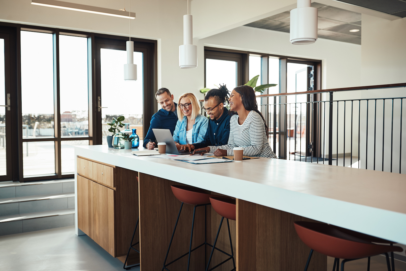 Laughing businesspeople working together on a laptop in an office