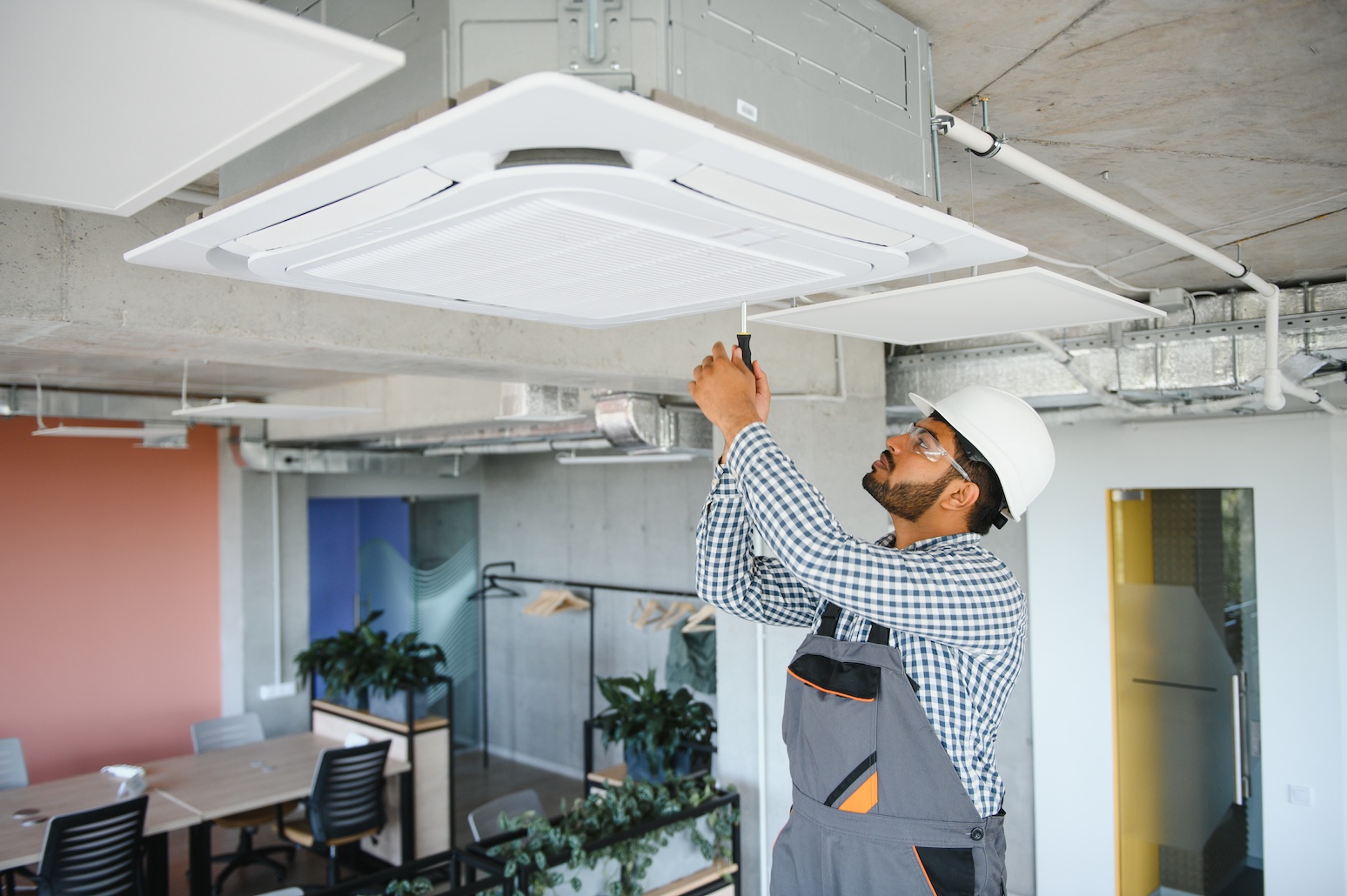 Professional technician maintaining modern air conditioner indoors. Space for text